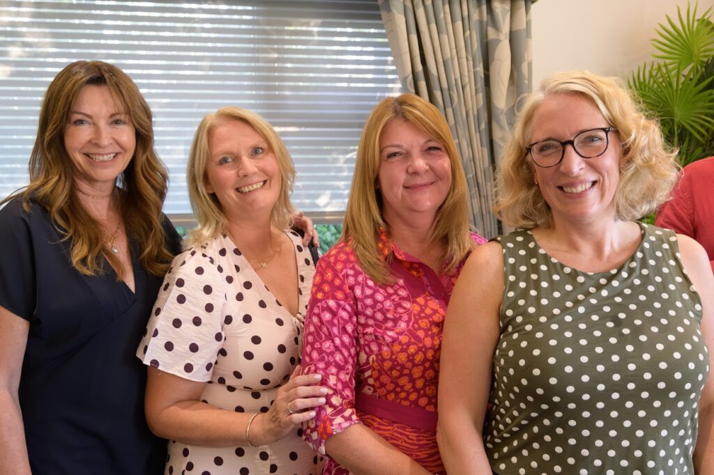 Four women smiling together at an event