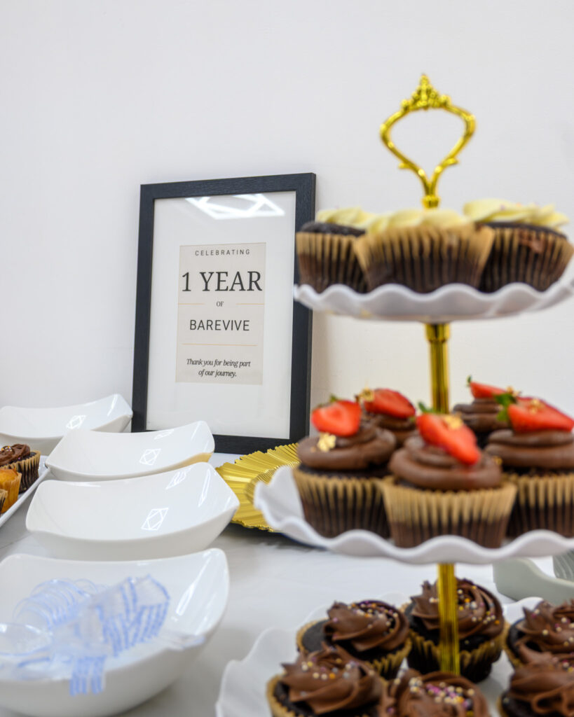 Cupcakes topped with strawberries beside a 1 Year BareVive sign at the clinic's anniversary