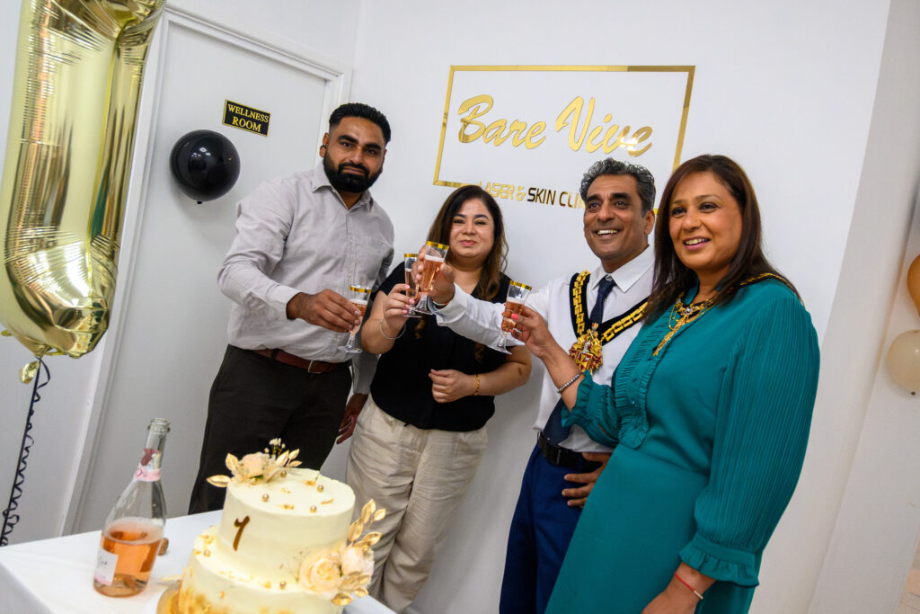 Guests raising a toast beside a gold-decorated cake at BareVive Laser & Skin Clinic's first anniversary