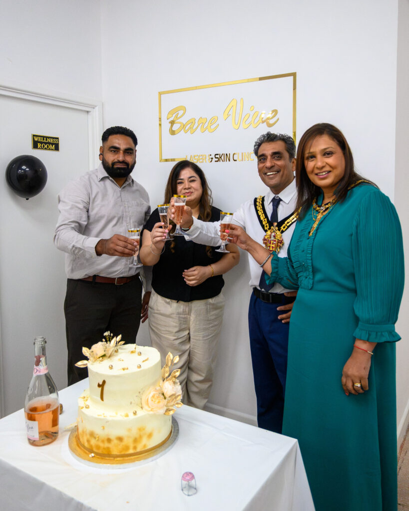 Guests raising a toast beside the anniversary cake at BareVive Laser & Skin Clinic